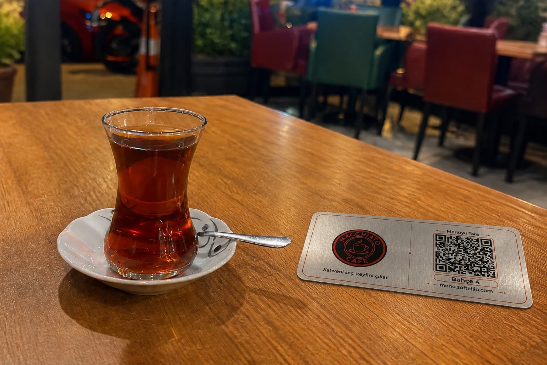 Macchiato Cafe masasında çay ve doğrulanmış Softellio QR menü plakası
